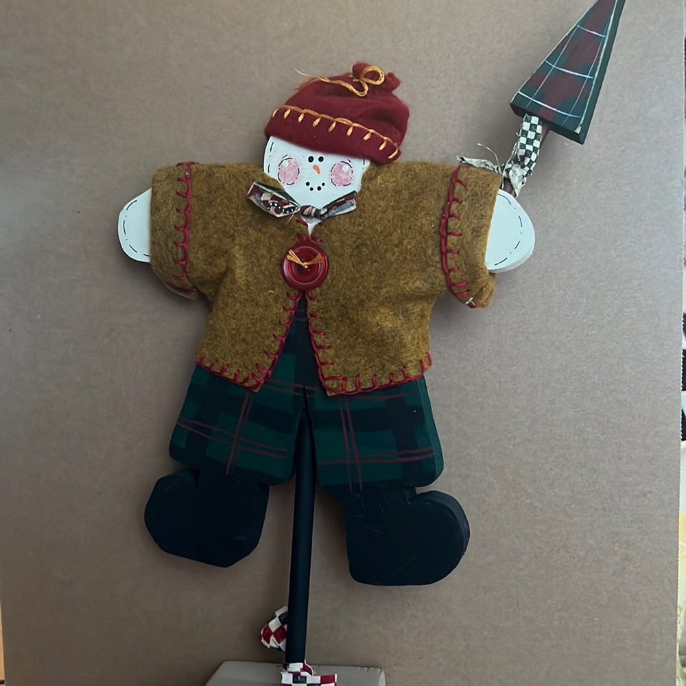 Cute snowman holding a Christmas tree and wearing a patriotic bow tie.